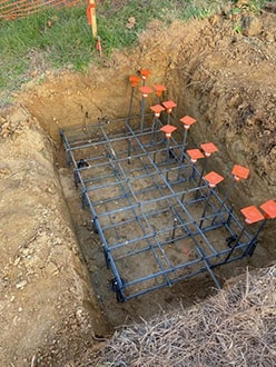 Photo of concrete footings being set for wooden arch bridge.